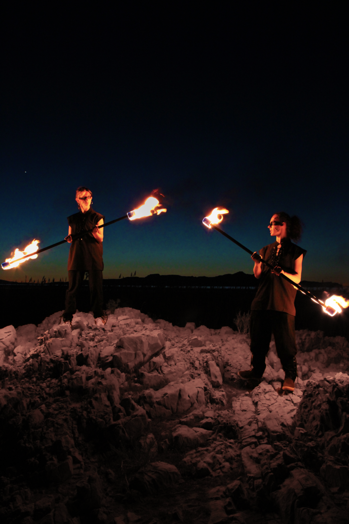 Two performers with flaming staffs on rocks